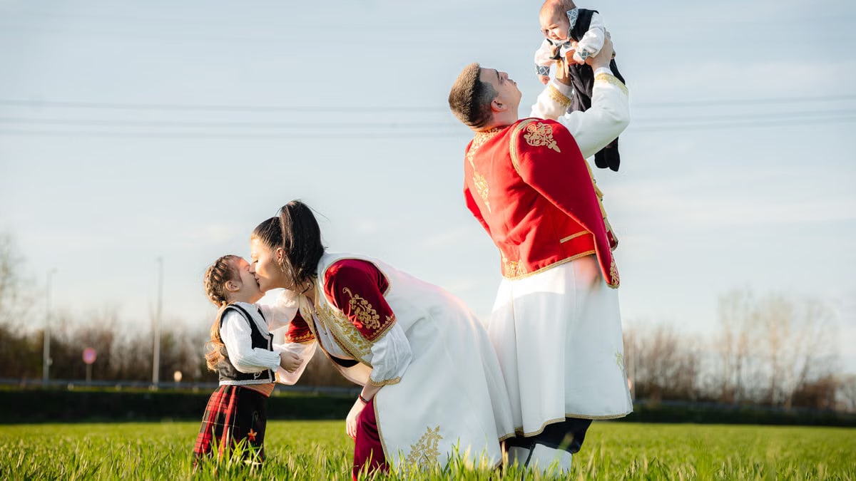 Joyful family in traditional attire playing in a sunny field, embracing cultural heritage.